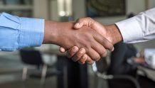 Two people in dress shirts shaking hands