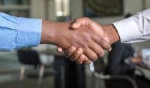 Two people in dress shirts shaking hands